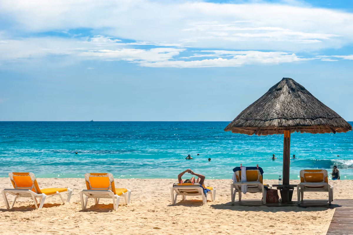 Beach umbrellas and loungers beside turquoise water in Cancún
