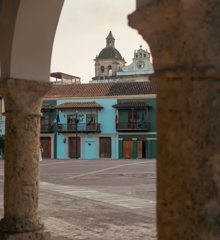 Stone arches frame a plaza and church tower in Cartagena