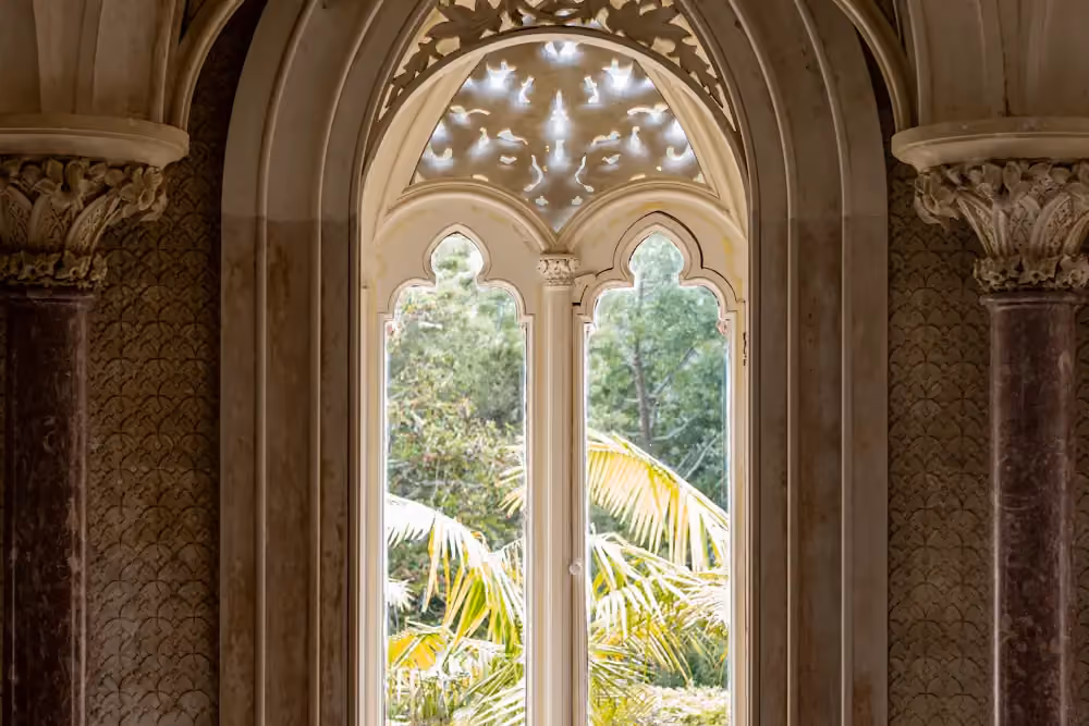 Ornate carved window framing greenery at Monserrate Palace in Sintra