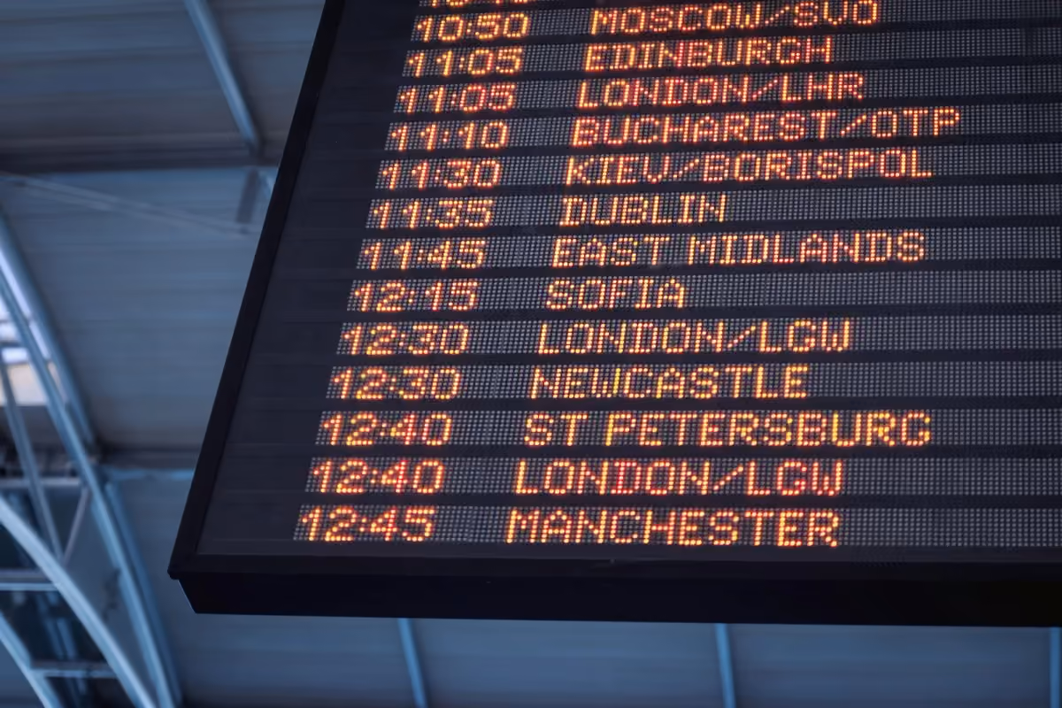 An airport flight information board viewed from below