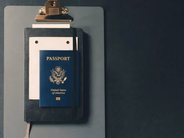 A closed passport on a clipboard with papers