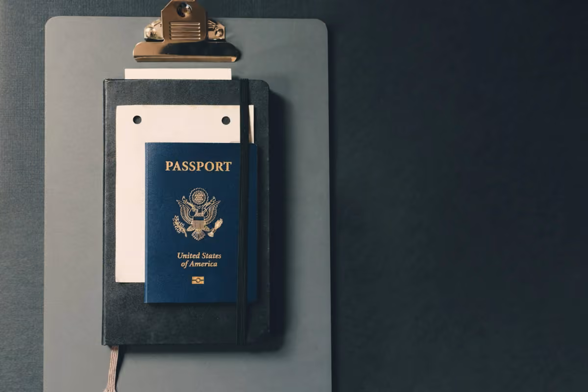A closed passport on a clipboard with papers