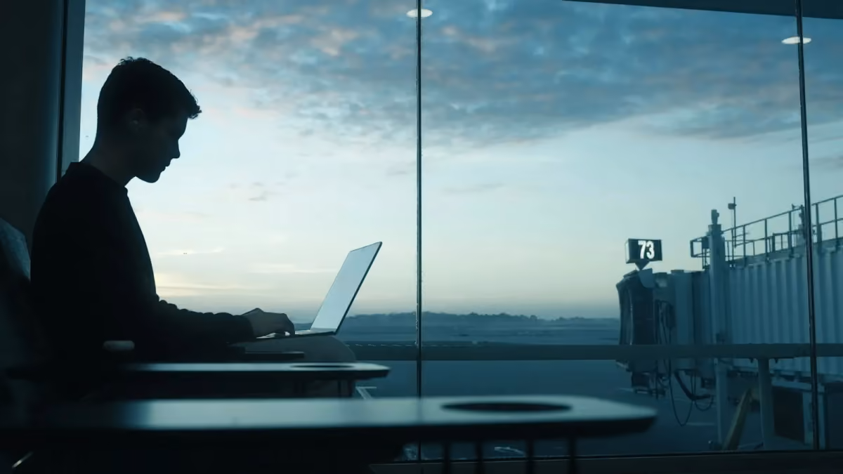 A traveler using a laptop beside an airport window