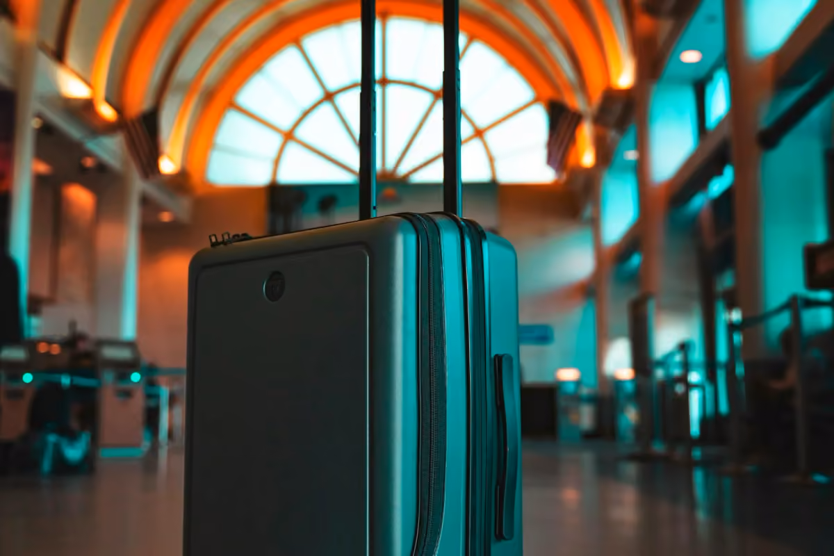 An upright suitcase in a sunlit airport terminal