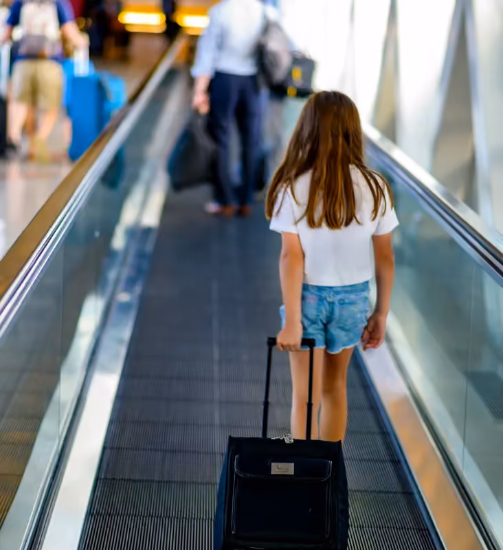 A traveler with a suitcase on a moving walkway at Boston Logan Airport