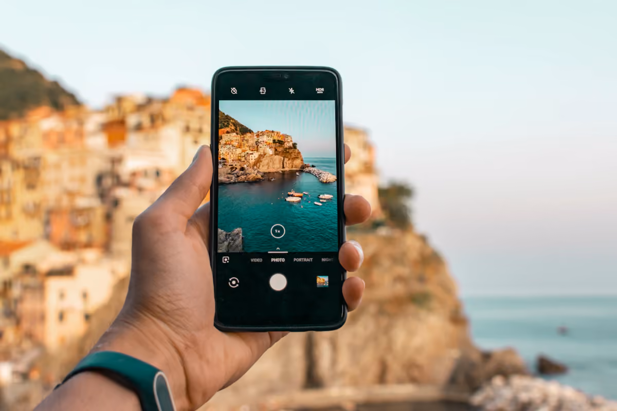 A traveler holding a smartphone above the coast at Manarola in Italy