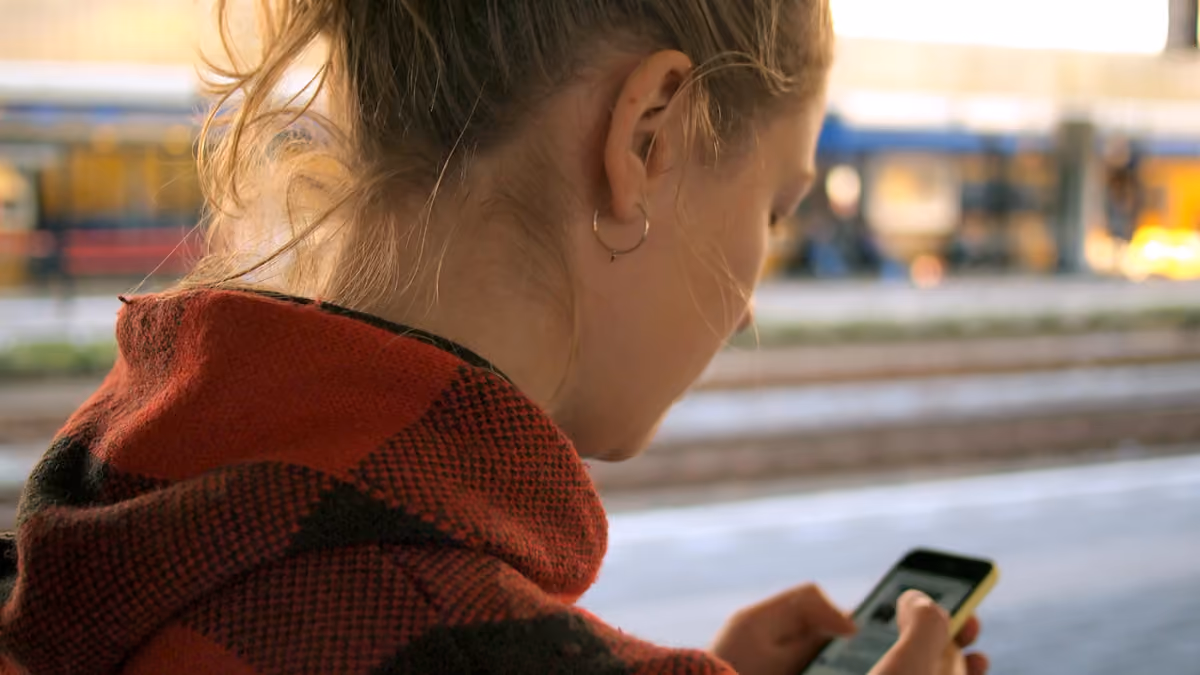 A traveler checking a smartphone at Leiden Centraal railway station